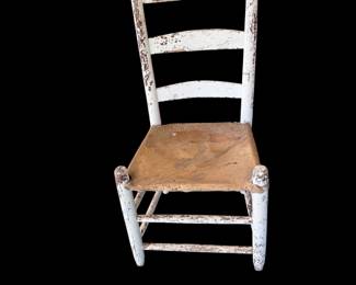 vintage primitive ladder-back wooden chair with chippy white paint and a worn rush Seat. 