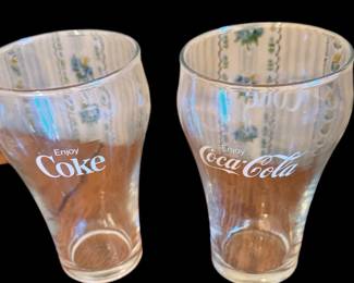 This is a set of vintage clear glass tumblers featuring white Coca-Cola and "Enjoy Coke" branding from the 1970s.