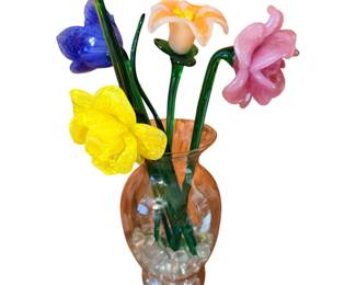 colorful arrangement of hand-blown glass flowers in a small glass vase filled with clear decorative beads.