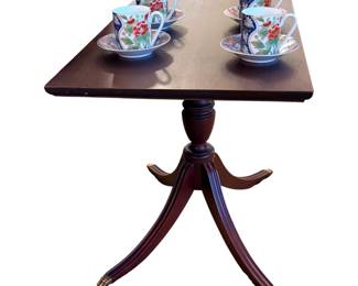 a vintage mahogany wood pedestal side table, often designed in a traditional or Duncan Phyfe style featuring curved tripod legs with brass claw feet