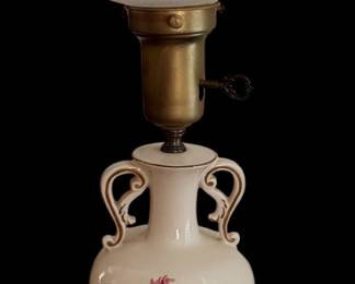 vintage porcelain urn-style table lamp featuring a floral motif, double scroll handles, and a hurricane-style frosted or swirl glass shade