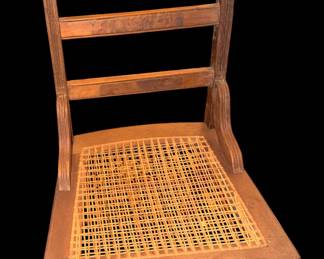 This is  a late 19th-century antique Victorian Eastlake wooden side chair featuring a ladder-back design, a hand-woven cane seat, and turned legs with stretchers.