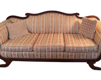 a vintage Duncan Phyfe-style camelback sofa featuring a carved dark wood frame and striped upholstery