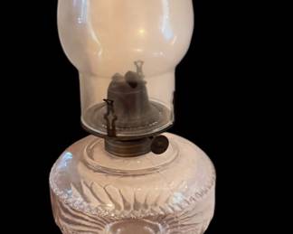 clear pressed-glass pedestal kerosene oil lamp with a bulbous font, a fluted pedestal base, a metallic burner,