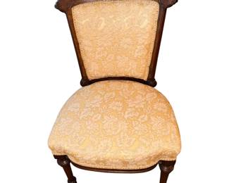 This is an antique Victorian-era side or parlor chair featuring an ornate dark wood frame with carved details and soft yellow floral patterned upholstery.