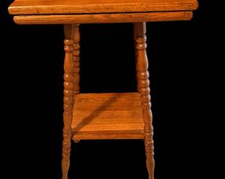 A vintage two tier parlor table with a square top, spool or bobbin-turned spindle legs, and a smaller open lower shelf.