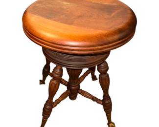 This  an antique adjustable swivel piano stool from the late 19th or early 20th century, typically featuring turned wooden legs and glass ball-and-claw feet. 
