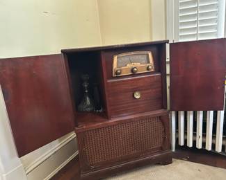 Vintage tube radio in wooden console cabinet with antique oil lamp