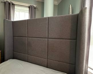 Upholstered king-size bed with tufted gray headboard in bedroom with crown molding