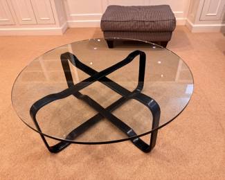 Round glass coffee table with cross base in black.