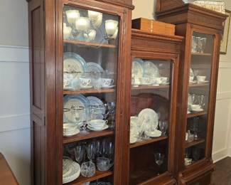 Antique china hutch displaying china, crystal stemware, and silver serving trays