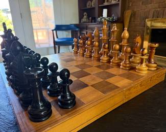 Close up of carved wood chess set with weighted pieces on wood board