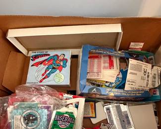 Box of collectibles with Superman book and sealed baseball card packs