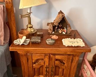 Oak nightstand cabinet with swing arm brass lamp and nativity display