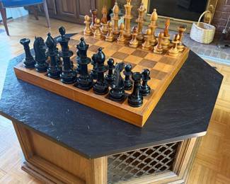 Carved wood chess set on inlaid board with slate top coffee table and wine rack base