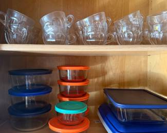 Cabinet of glass mugs and Pyrex glass storage containers with lids