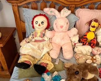 Raggedy Ann doll with plush bunny, teddy bears and vintage dolls on bed