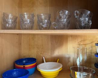 Cabinet with glass tumblers, mugs and nested plastic mixing bowls