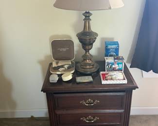Three drawer wood nightstand with brass table lamp and jewelry box