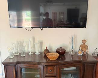 Wood media console with glass doors, flat screen TV and milk glass vase collection