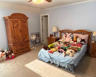 Bedroom with oak armoire, bed, nightstands and large stuffed animal collection