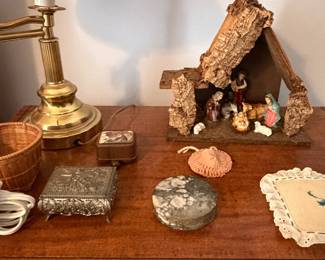 Wood nativity stable set with brass candlestick lamp, silver box and doilies on side table