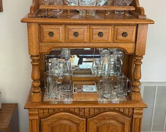Oak dry sink bar cabinet with mirrored back, glass decanters and barware