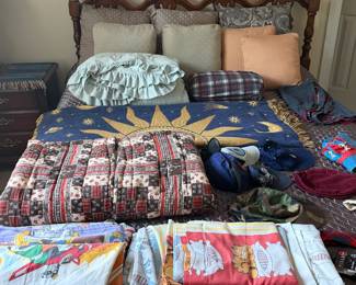 Carved wood bed with quilts, vintage bedsheets, pillows and linens