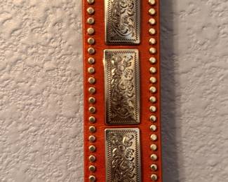 Brown leather belt featuring engraved silver-tone buckle, keeper, and tip with matching conchos and stud accents. Includes original P & G Collection hang tag. A classic Western-style accessory for everyday wear or cowboy attire. Sold as found.