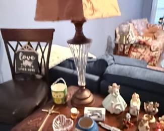 Table Lamp & Home Décor Collection – Table lamp featuring a crystal-style column and tapered fabric shade, displayed with an assortment of decorative figurines, religious décor, collectibles, and tabletop accessories. Items sold individually unless noted.