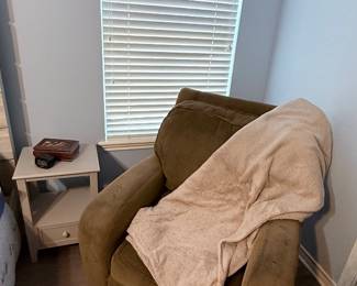 Upholstered Accent Chair – Comfortable upholstered accent chair in a soft olive green fabric with wide arms and plush cushions. A versatile seating option for a living room, bedroom, or reading nook. Also pictured is a white side table. Items sold individually unless noted.