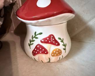 Ceramic Mushroom Cookie Jar – Ceramic mushroom-shaped cookie jar featuring a red lid with white polka dots and hand-painted mushroom accents. A whimsical addition to a kitchen, cottagecore décor, or mushroom collection. Sold as found.
