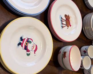 holiday dinnerware featuring festive Santa, snowman, gingerbread, and reindeer designs with coordinating colored rims. Includes bowls, mugs, and matching serving pieces. A cheerful collection for holiday meals and seasonal entertaining. Items sold individually unless noted.