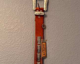 Brown leather belt featuring engraved silver-tone buckle, keeper, and tip with matching conchos and stud accents. Includes original P & G Collection hang tag. A classic Western-style accessory for everyday wear or cowboy attire. Sold as found.