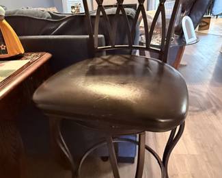 Swivel Bar Stool – Upholstered swivel bar stool featuring a dark wood back with decorative lattice detailing, a padded faux leather seat, and metal footrest. A stylish seating option for a kitchen island, breakfast bar, or game room. Sold individually unless noted.