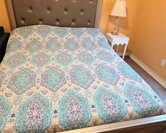 Upholstered bed featuring a tufted headboard and matching footboard, white one-drawer nightstand, crystal-style table lamp, and decorative accessories. A coordinated collection for a primary or guest bedroom. Items sold individually unless noted.