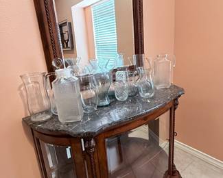 Vintage Curio Cabinet – Curved front curio cabinet featuring a decorative wood frame, marble-look top, mirrored back, and glass display shelves. Displayed with an assortment of glassware, including several Princess House pieces. A beautiful cabinet for showcasing crystal, collectibles, or decorative accents. Items sold individually unless noted.
