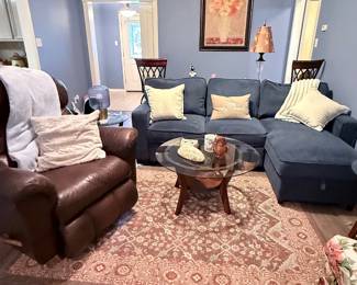 Living Room Furniture – Sectional sofa, leather recliner, glass-top coffee table, area rug, floor lamp, framed wall art, and accent décor. Items sold individually unless noted.