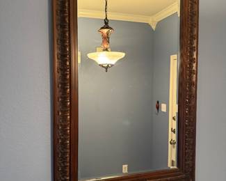 Large rectangular wall mirror featuring an intricately carved wood frame with rich decorative detailing. A timeless statement piece for an entryway, dining room, living room, or bedroom. Sold as found.