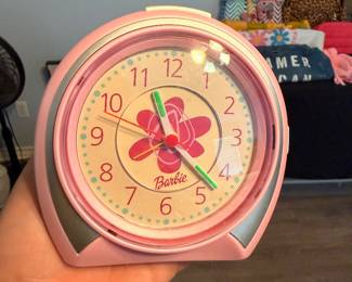 **Barbie Alarm Clock** – Pink Barbie alarm clock featuring a floral dial, colorful hands, and a classic tabletop design. A fun collectible for Barbie fans or a cheerful addition to a bedroom or display. Sold as found.