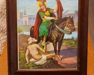 Framed religious print depicting Saint Martin of Tours sharing his cloak with a beggar on horseback. Finished in a classic wood frame, this timeless piece is ideal for a home, office, or devotional space. Sold as found.