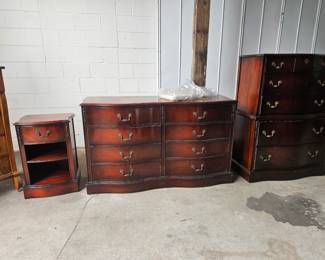 Beautiful matching three piece bedroom furniture set featuring a nightstand, long dresser, and tall chest of drawers with curved fronts, rich dark wood finish, and decorative brass tone hardware.