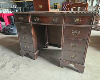 Beautiful vintage nine drawer kneehole desk with carved detailing, decorative brass hardware, and plenty of storage.
