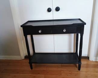 Traditional black wood console table featuring turned spindle legs and clear crystal knobs.