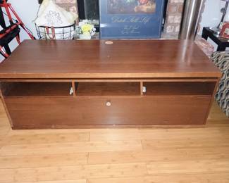 Front view of mid-century low-profile walnut TV stand featuring open media shelves and drawer.