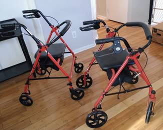 Pair of Drive Medical rollator walkers featuring built-in padded safety seats and hand brakes.
