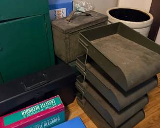 Mid-century green metal stackable desktop letter tray organizer
Condition: Fair
Stacked painted-metal desktop paper/letter trays with a wire side frame. Surface shows heavy dust, oxidation, and age wear. Secondary items in the scene, such as the cassette-recorder box and metal case/toolbox, are not included as separate identified items.