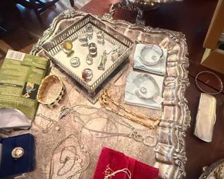 Vintage mixed costume jewelry lot with ornate trays and assorted rings, necklaces, and brooches
Condition: Good
Assorted costume jewelry lot displayed on ornate silver-tone trays. Visible contents include multiple chain necklaces, beaded strands, several rings, small pins or brooches, and a few boxed or carded pieces. The lot appears mixed by type, style, and likely maker, with no obvious complete set relationship among the pieces.