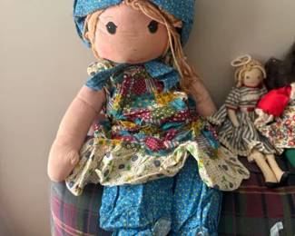 Holly Hobbie cloth rag doll with blue patchwork bonnet and dress
Condition: Good
Large cloth rag doll with a painted face, blue patterned bonnet, matching blue patchwork-style outfit, floral apron/skirt layers, blonde yarn hair, white legs, and black shoes. The style is consistent with vintage Holly Hobbie-type dolls. Background dolls are incidental and not included in the count.
