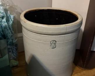Ceramic floor planter urn with dark interior and maker mark
Condition: Fair
One large cylindrical ceramic planter or urn with a wide rolled rim, light gray exterior, dark glazed interior, and a small centered front mark. Visible hairline crack near the rim and general surface wear. If there is a brand, it is not readable from the photo alone.